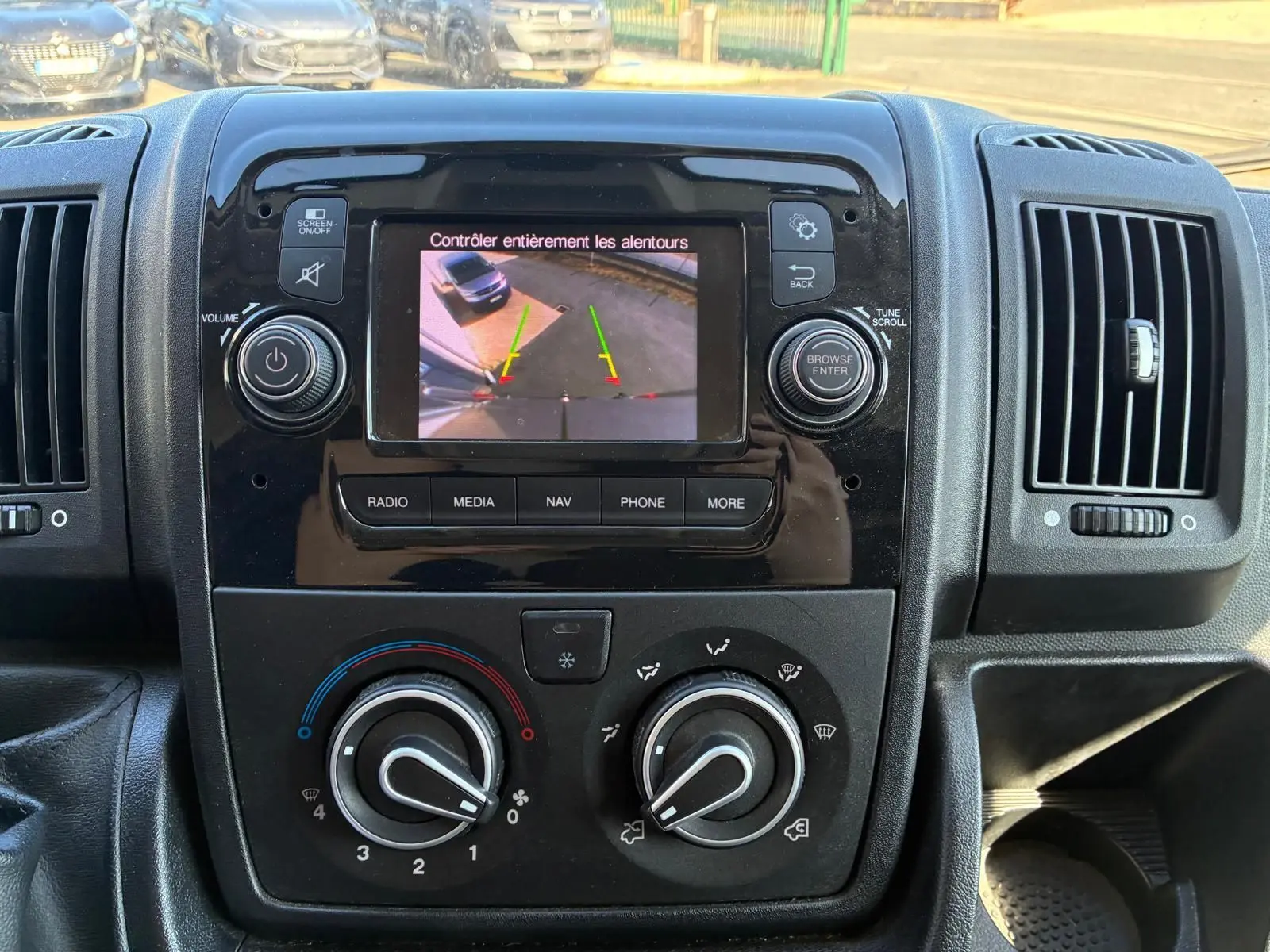 Vue rapprochée du tableau de bord du Peugeot Boxer 2019 avec écran de caméra de recul et commandes de climatisation.