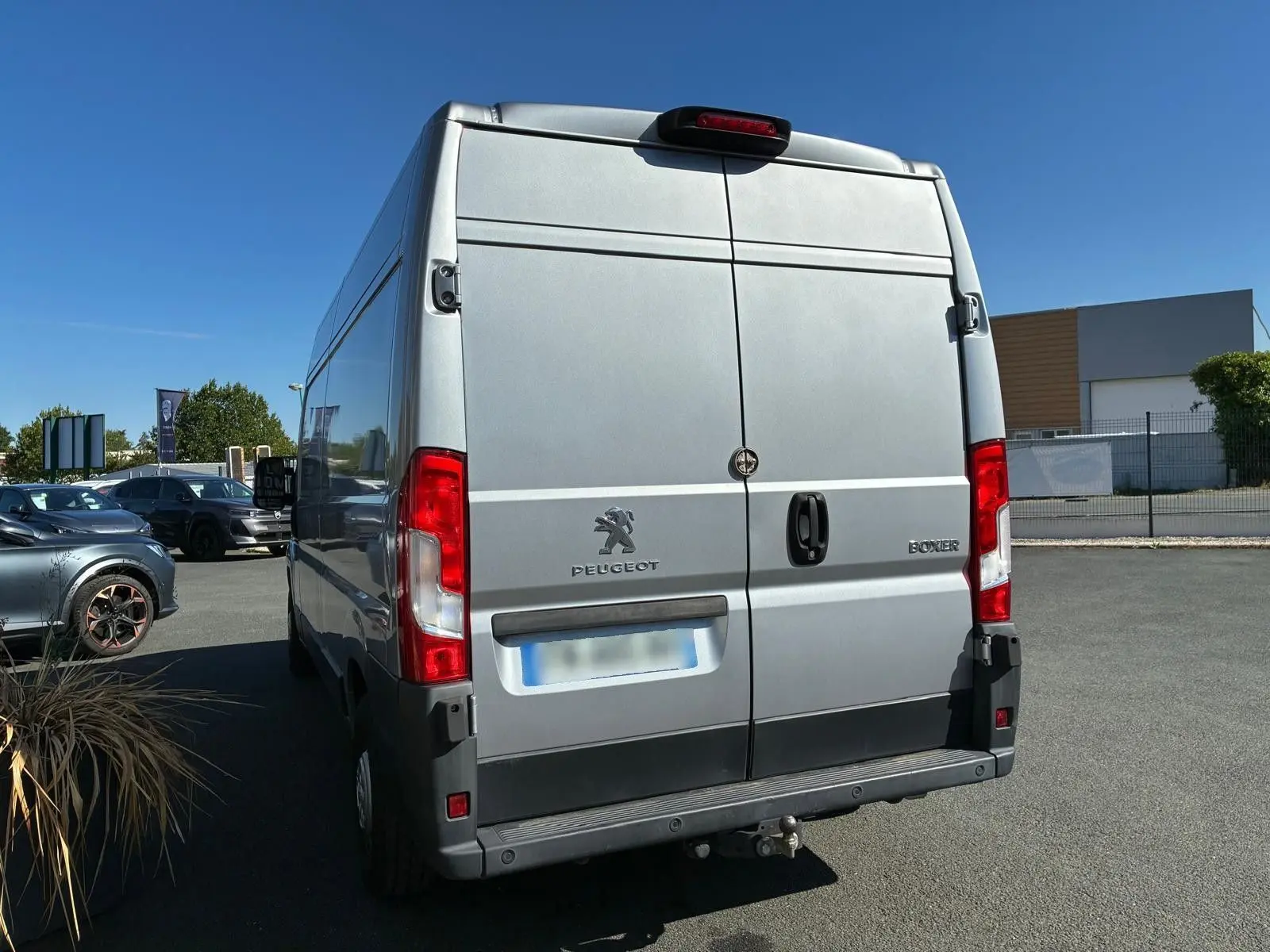 Vue arrière d'un Peugeot Boxer cabine approfondie gris 2019 avec porte double et attelage visible.