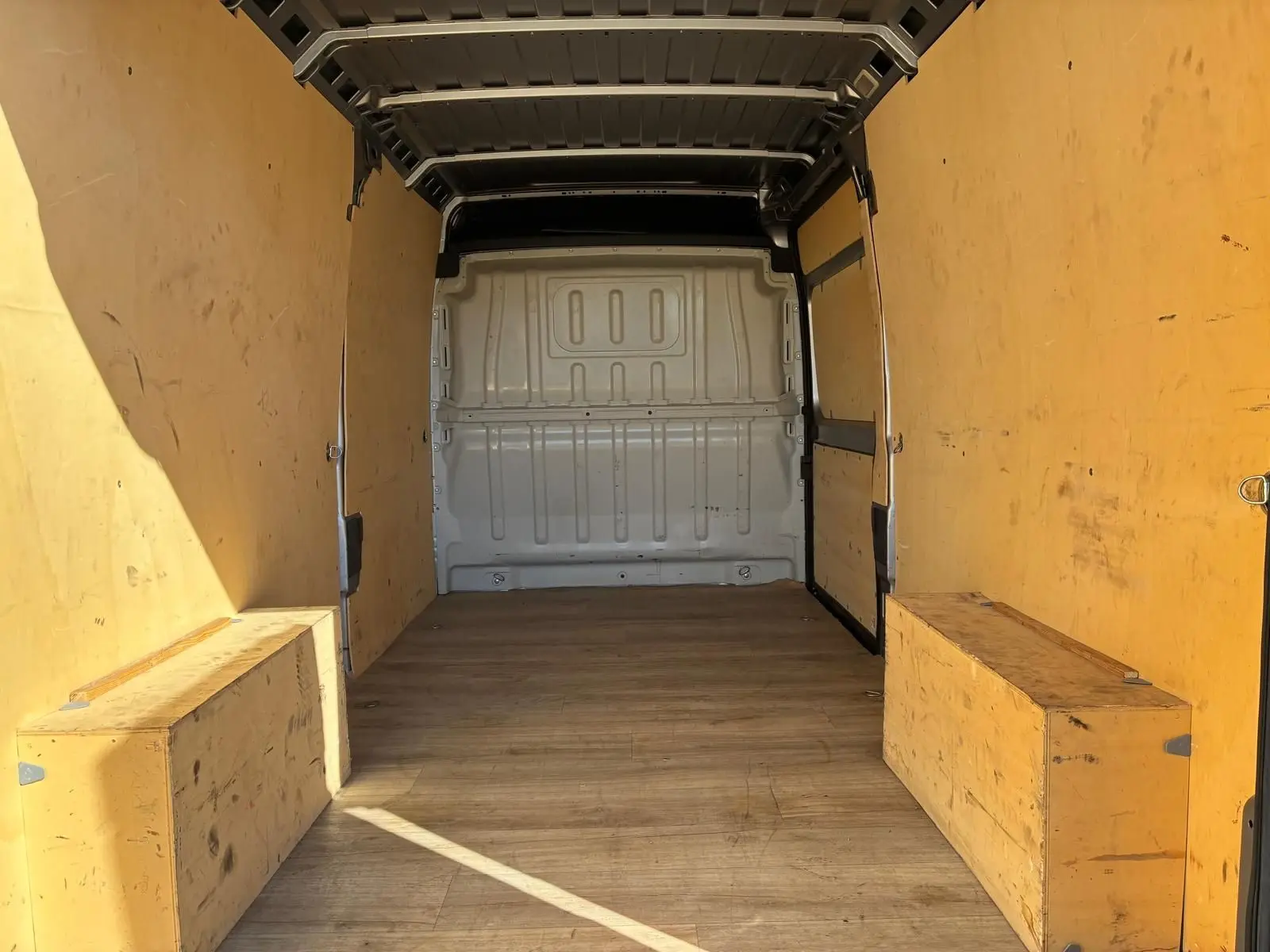 Vue intérieure de la zone de chargement du Peugeot Boxer gris, montrant l’espace vide avec parois en bois clair.