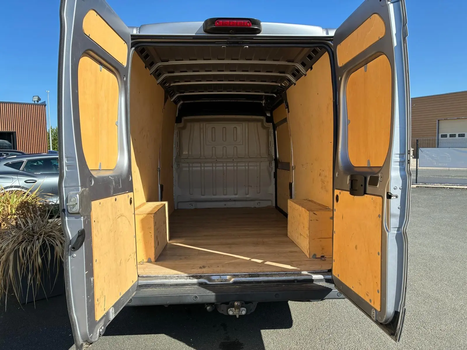 Vue arrière du Peugeot Boxer cabine approfondie gris 2019, portes ouvertes révélant un espace de chargement en bois clair.