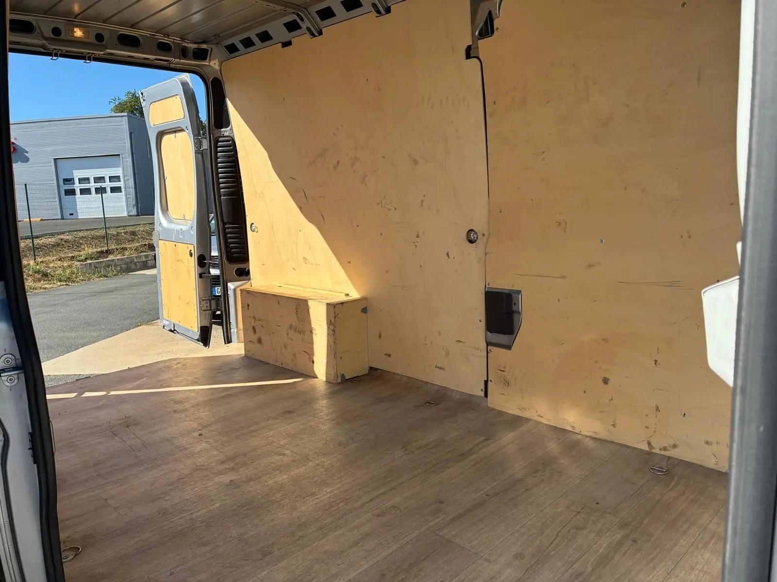 Intérieur du coffre du Peugeot Boxer gris 2019, vue depuis l'arrière droit avec portes ouvertes et revêtement bois.