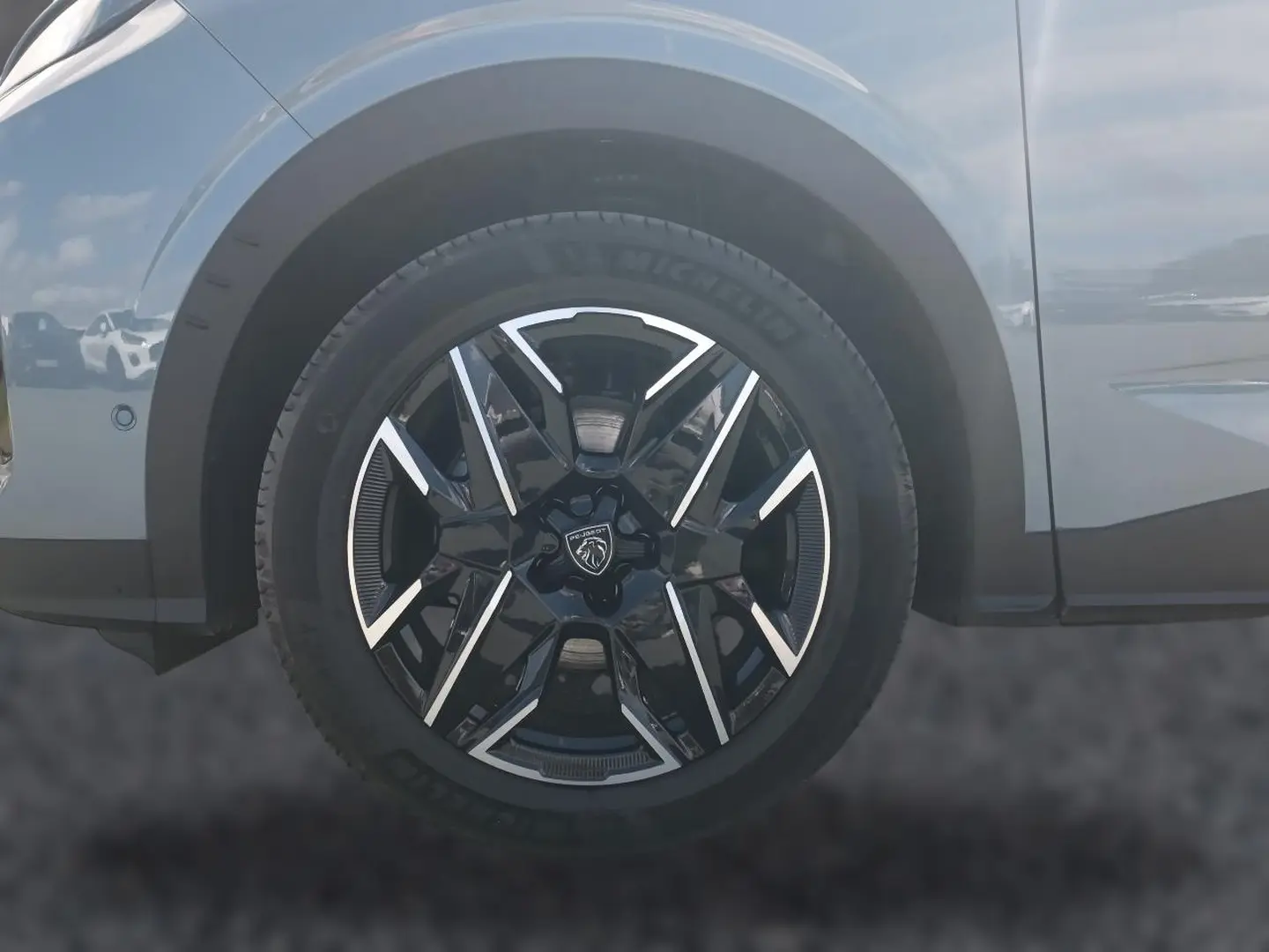 Gros plan sur la roue avant gauche noire et argentée du Peugeot 3008 bleu, avec logo lion central visible.