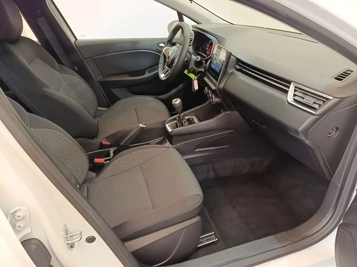 Vue intérieure côté conducteur d'une Renault Clio Business TCe 90 blanche, sièges tissu gris et tableau de bord moderne.