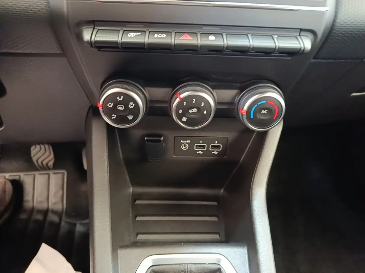 Gros plan sur les commandes de climatisation et ports USB de la Renault Clio Business TCe 90 blanche, intérieur noir.