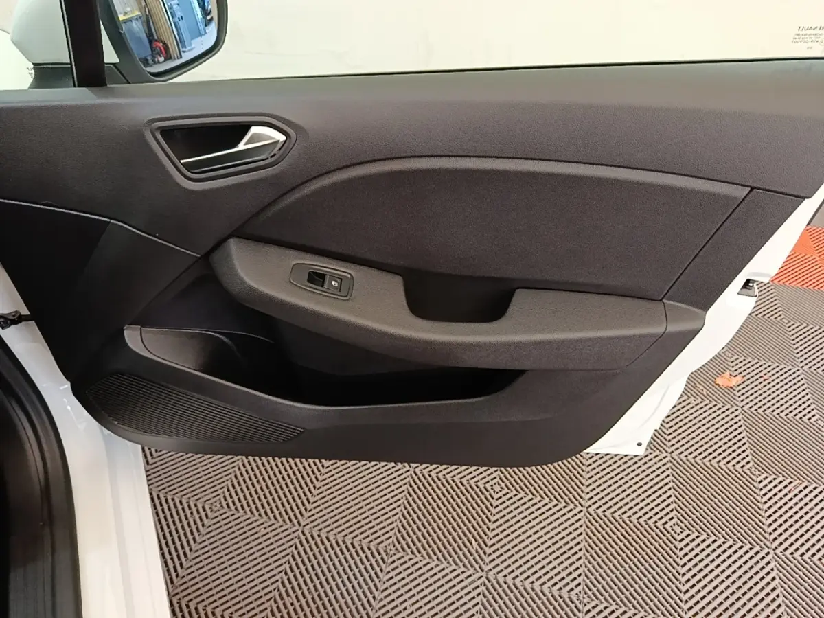 Vue rapprochée de la porte avant gauche blanche d'une Renault Clio 2020, avec panneau intérieur noir et commande de vitre.