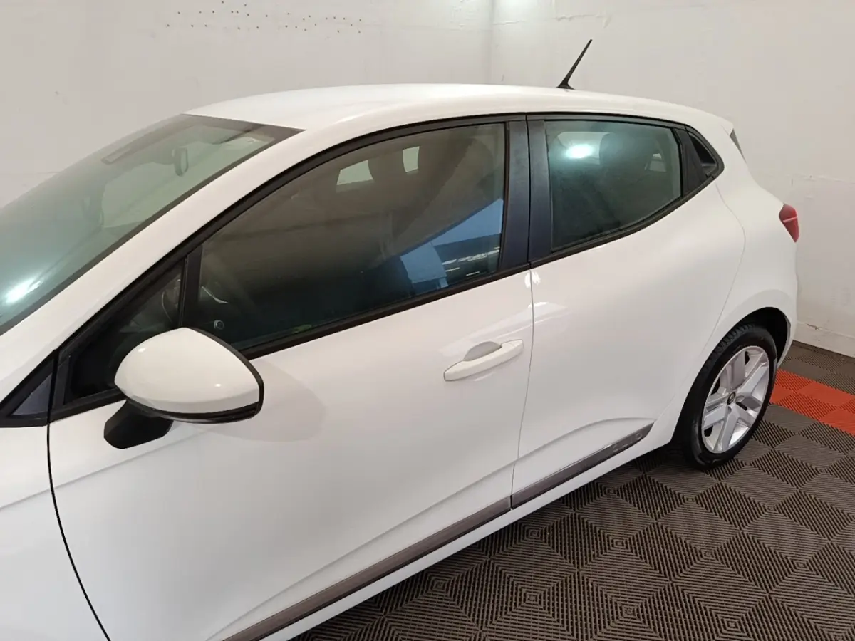 Vue latérale côté gauche d'une Renault Clio Business blanche, mettant en valeur la ligne épurée et les rétroviseurs assortis.