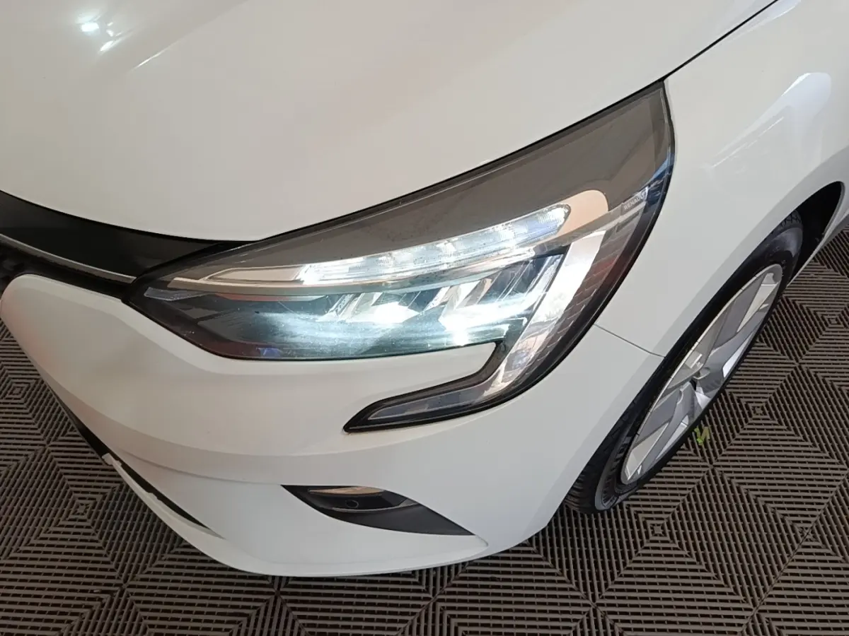 Gros plan sur l'avant droit blanc d'une Renault Clio 2020, mettant en valeur le phare LED et la roue.