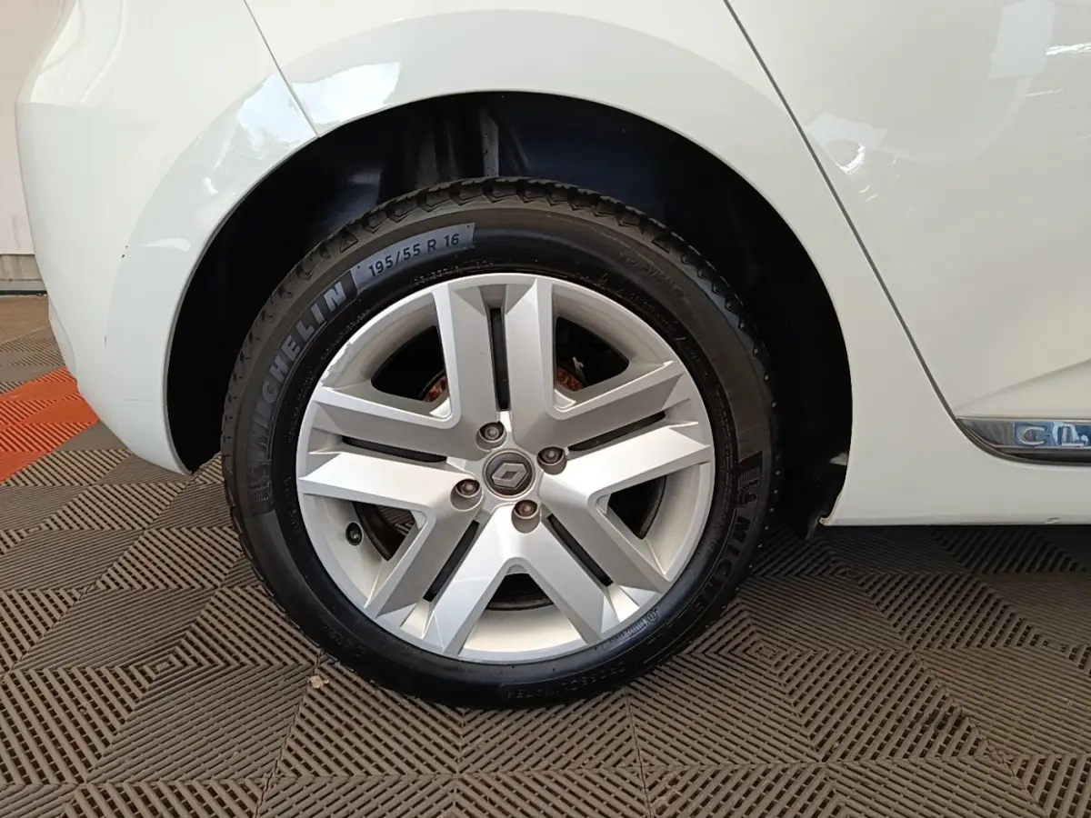 Gros plan sur la roue arrière droite d’une Renault Clio blanche, avec jante alliage et logo Renault central.
