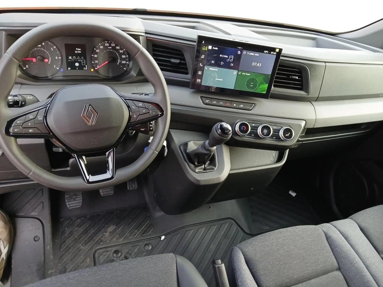 Vue intérieure avant du tableau de bord du Renault Master L2H2 2026, volant multifonction et écran tactile central visibles.