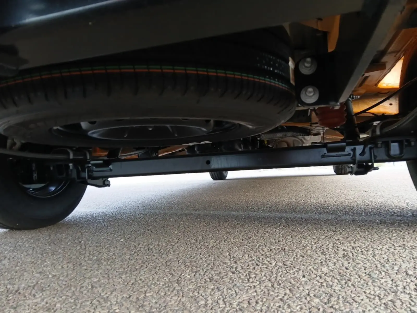 Vue en contre-plongée sous un Renault Master orange 2026, montrant la roue de secours et le châssis arrière.