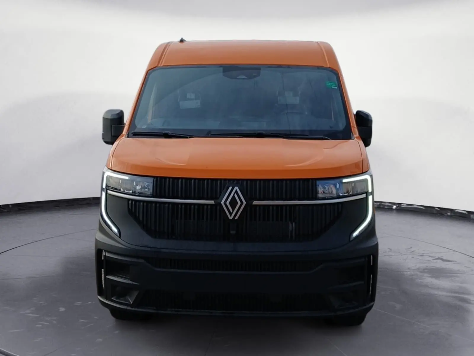 Vue frontale du Renault Master L2H2 2026 orange avec calandre noire et feux LED en forme de C.