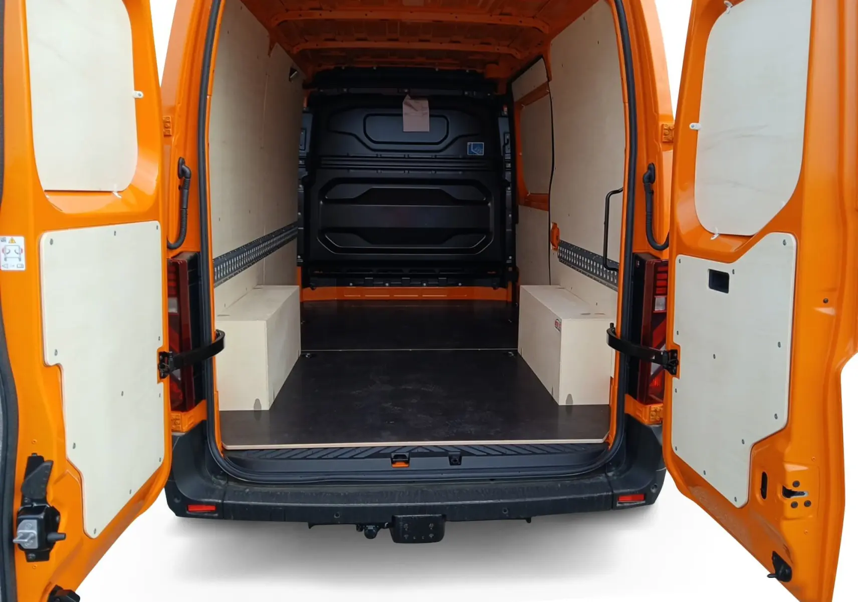Vue arrière des portes ouvertes du Renault Master orange, montrant l'intérieur spacieux avec habillage bois et plancher noir.