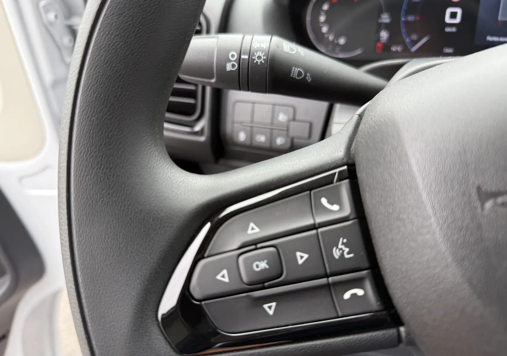 Gros plan sur le volant noir du Citroën Jumper blanc 2025, avec commandes multifonctions et tableau de bord en arrière-plan.