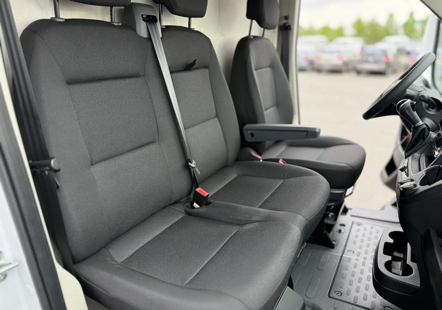 Vue intérieure côté conducteur du Citroën Jumper L3H2 2025, sièges tissu gris et tableau de bord visible.