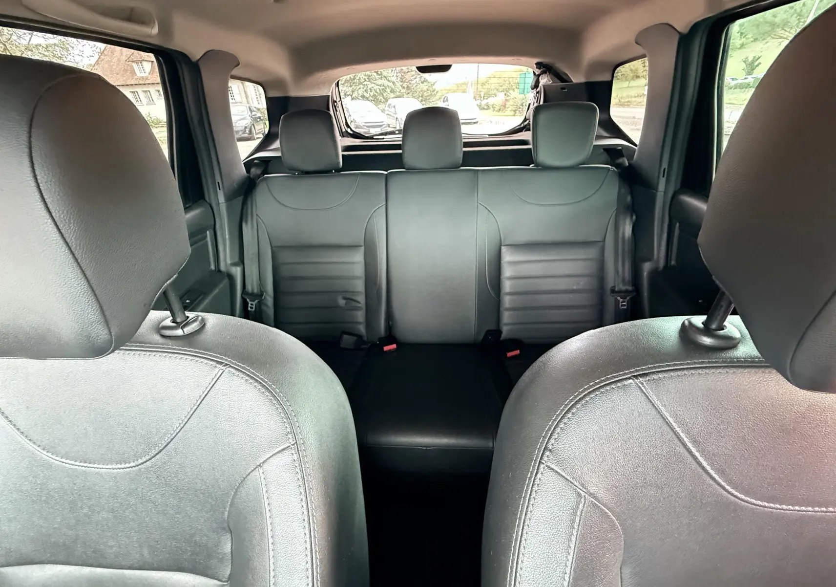 Vue intérieure arrière du Dacia Duster 2017, sièges en cuir noir et banquette arrière trois places visibles.