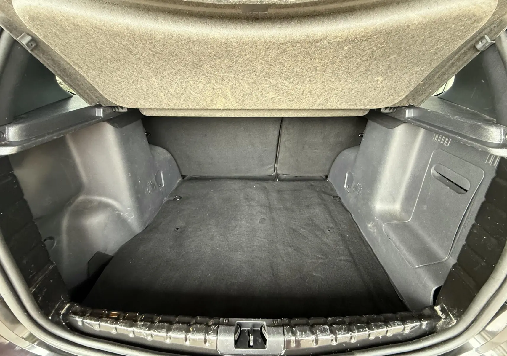 Coffre ouvert du Dacia Duster noir métal 2017, vue intérieure montrant l'espace de chargement et la moquette noire.