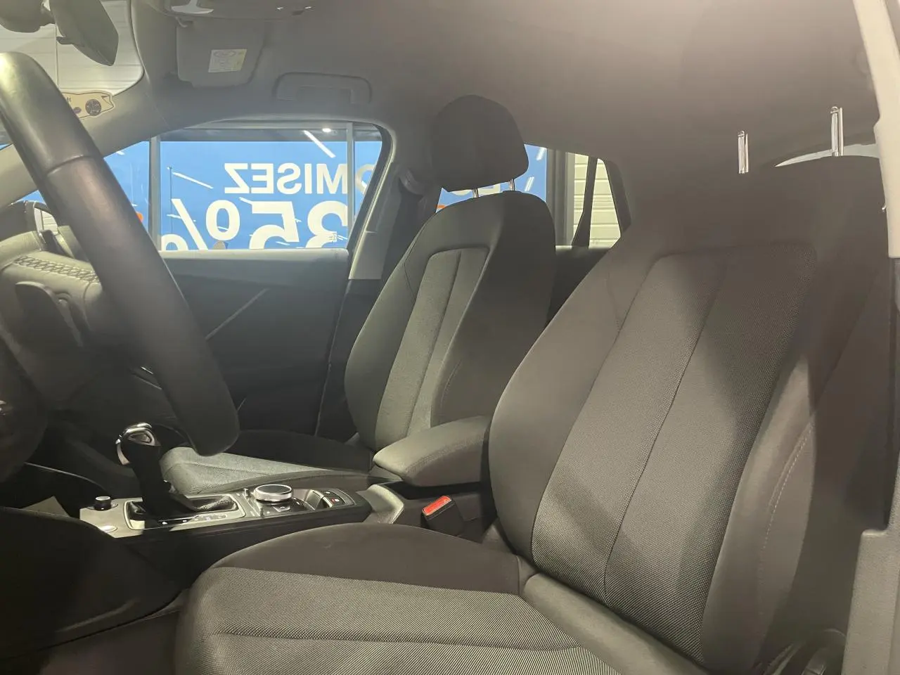 Vue intérieure côté droit des sièges avant en tissu noir de l'Audi Q2 2023 avec console centrale et levier de vitesses.