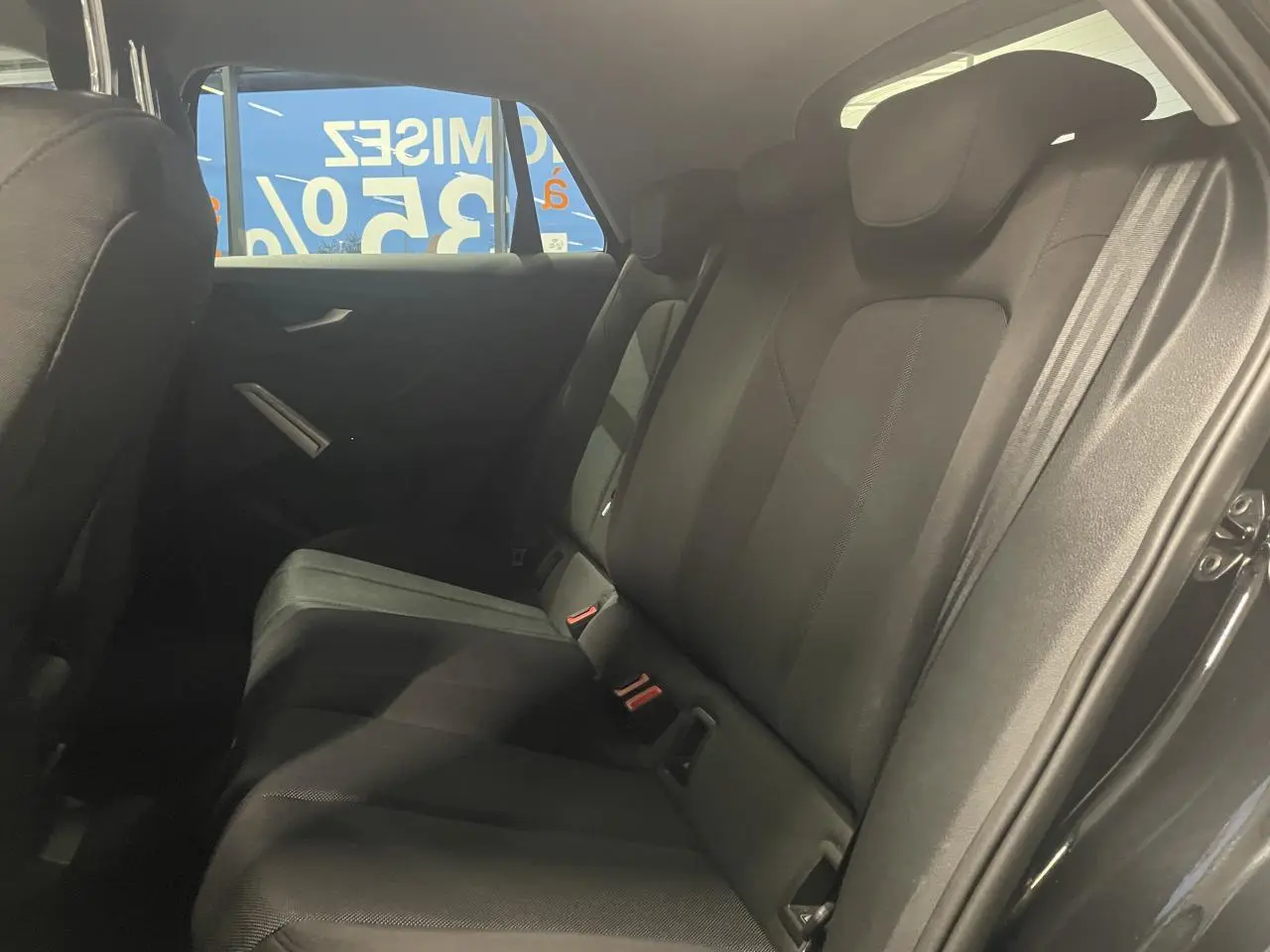 Vue intérieure du siège arrière droit de l'Audi Q2 noir métallisé, avec sellerie tissu et ceinture de sécurité visible.