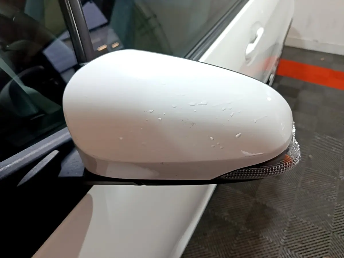 Rétroviseur droit blanc de la Toyota Yaris 1.5 VVT-I Hybrid France Business vu de près avec clignotant intégré.
