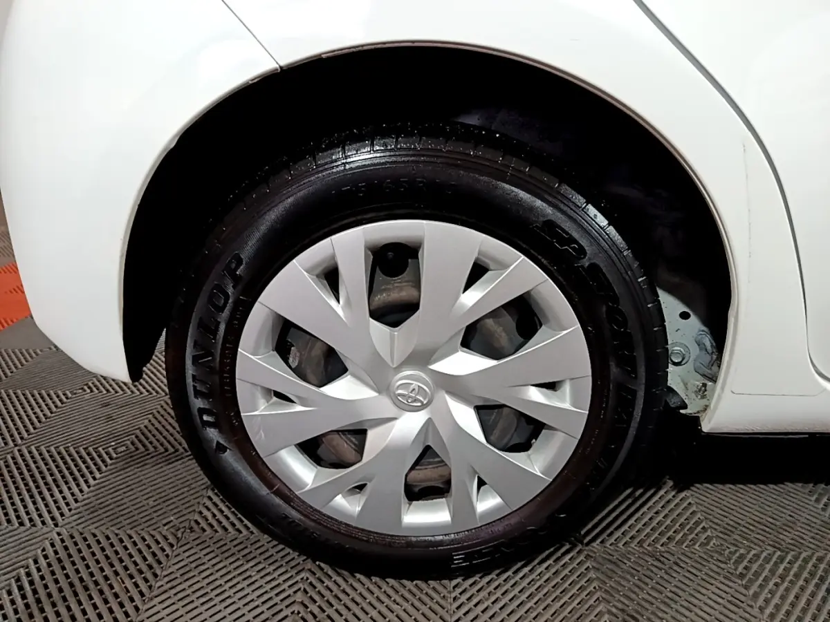 Gros plan sur la roue arrière droite blanche d'une Toyota Yaris 1.5 VVT-I Hybrid avec enjoliveur argenté.