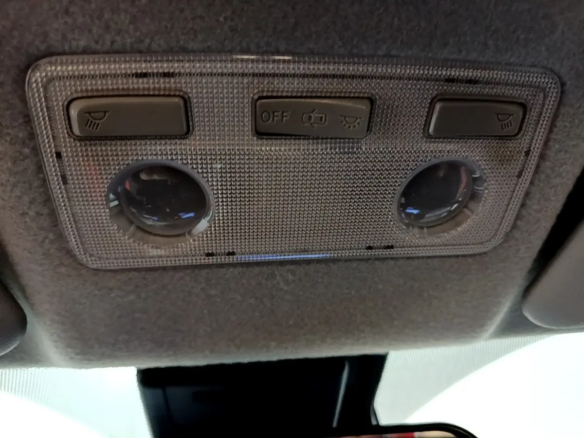 Plafonnier intérieur gris avec commandes d’éclairage et deux lampes rondes dans une Toyota Yaris blanche, vue de dessous.