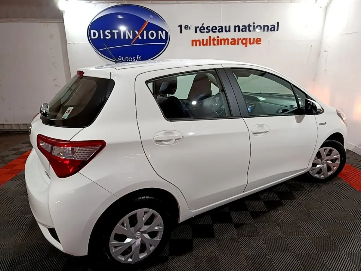 Vue 3/4 arrière droite d'une Toyota Yaris blanche 2019 hybride, avec jantes alliage et vitres teintées.