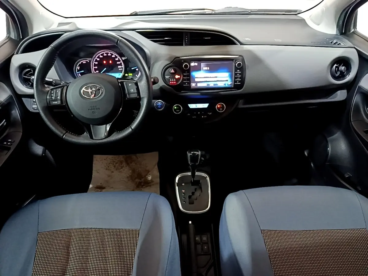 Vue intérieure avant de la Toyota Yaris 1.5 Hybrid 2019, volant cuir alu multifonctions et écran tactile central.