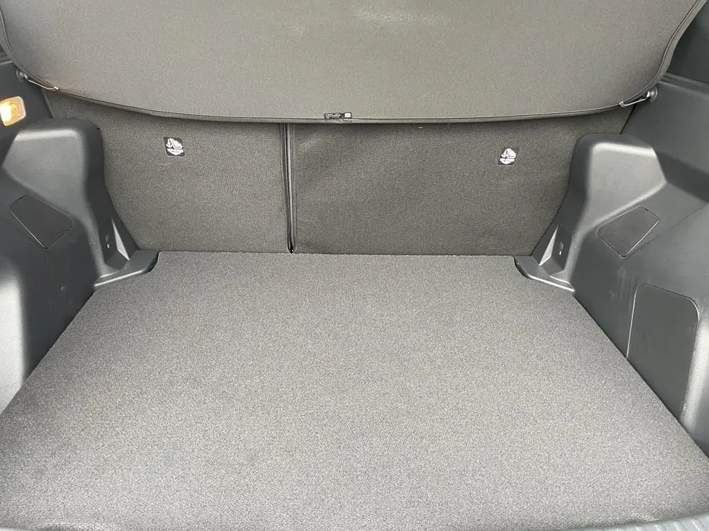 Coffre spacieux gris clair de la Toyota Yaris Cross 1.5 Hybrid 130h, vue intérieure arrière avec banquette rabattue.