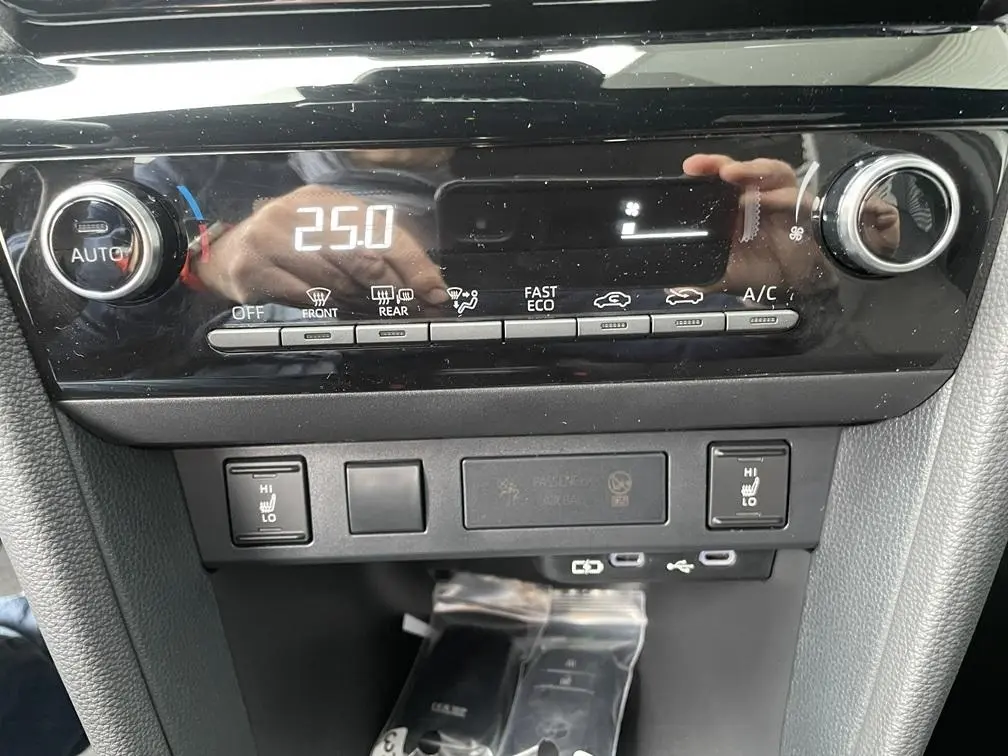 Gros plan sur la console centrale noire du Toyota Yaris Cross 2026, affichant la climatisation digitale et commandes chauffantes.