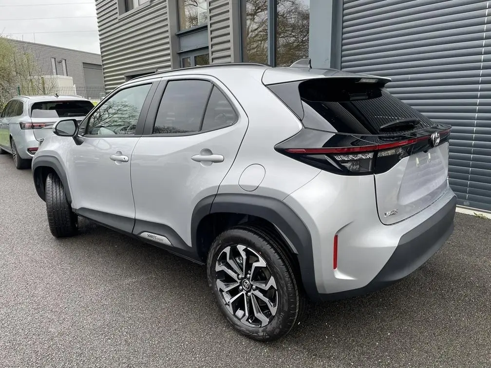 Vue 3/4 arrière droite d'une Toyota Yaris Cross gris clair avec jantes alliage et feux arrière LED noirs.