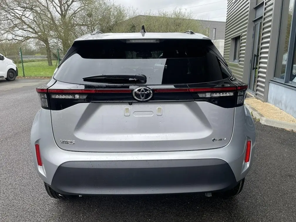 Vue arrière de la Toyota Yaris Cross gris clair 2026 avec feux arrière en bandeau et logo Toyota central.