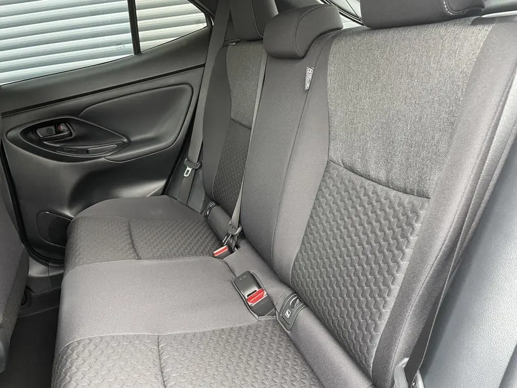 Vue intérieure côté gauche des sièges arrière gris foncé de la Toyota Yaris Cross 2026 avec ceinture de sécurité et porte.