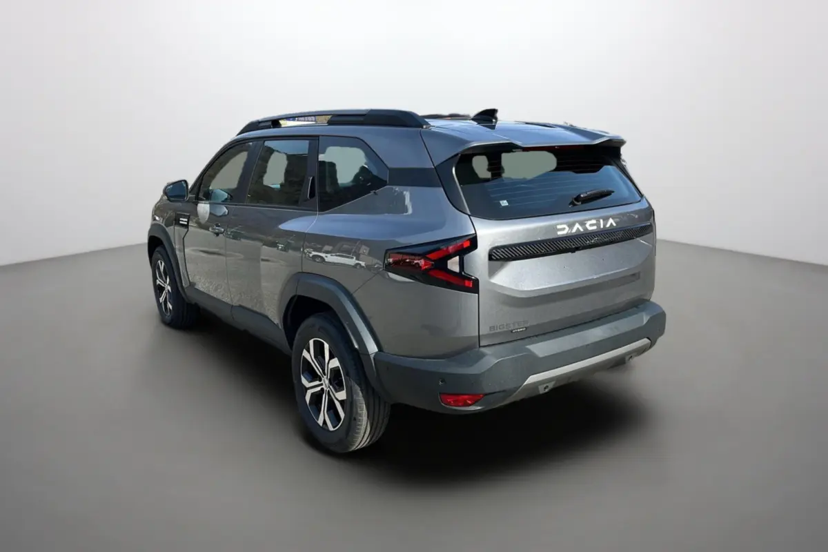 Vue 3/4 arrière droit du Dacia Bigster gris schiste avec barres de toit et jantes alu 17 pouces visibles.