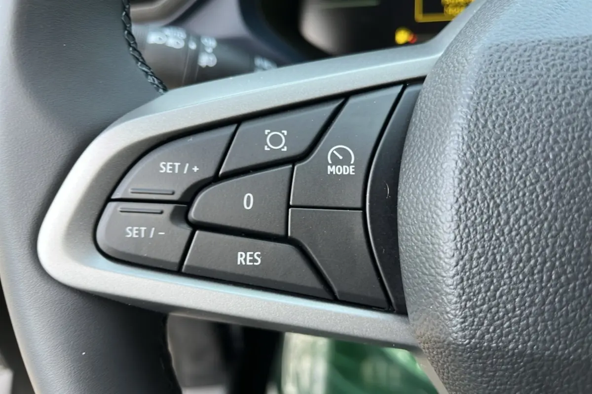 Gros plan sur les commandes de régulateur de vitesse au volant cuir du Dacia Bigster Hybrid 155 Expression Plus.