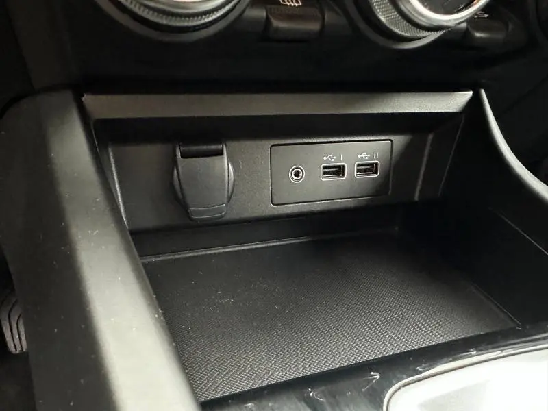 Prise USB et prise jack en gros plan dans la console centrale noire du Renault Arkana 2025, version hybride.