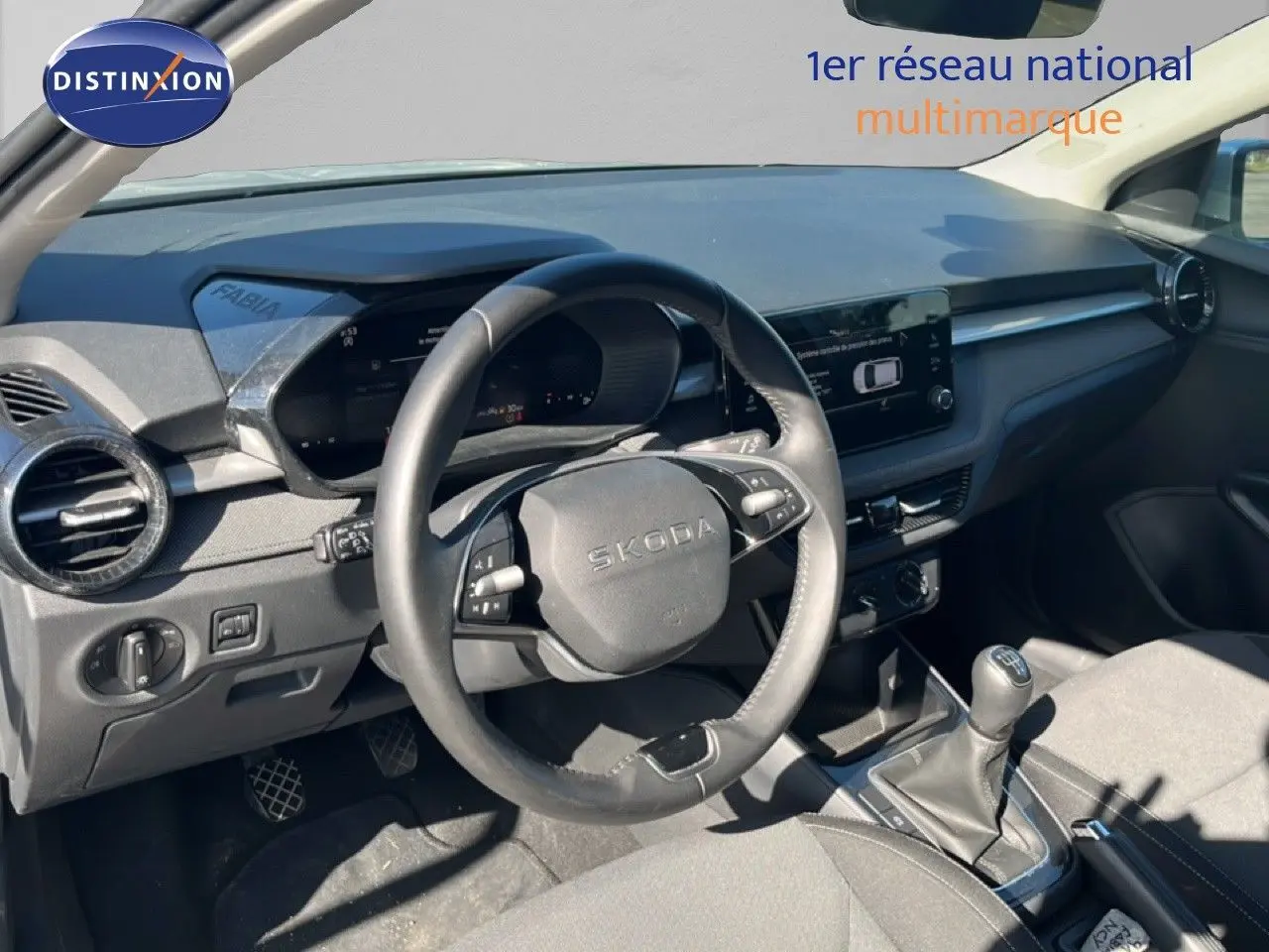 Vue intérieure côté conducteur du tableau de bord et volant noir d'une Skoda Fabia 2025 en tissu gris.