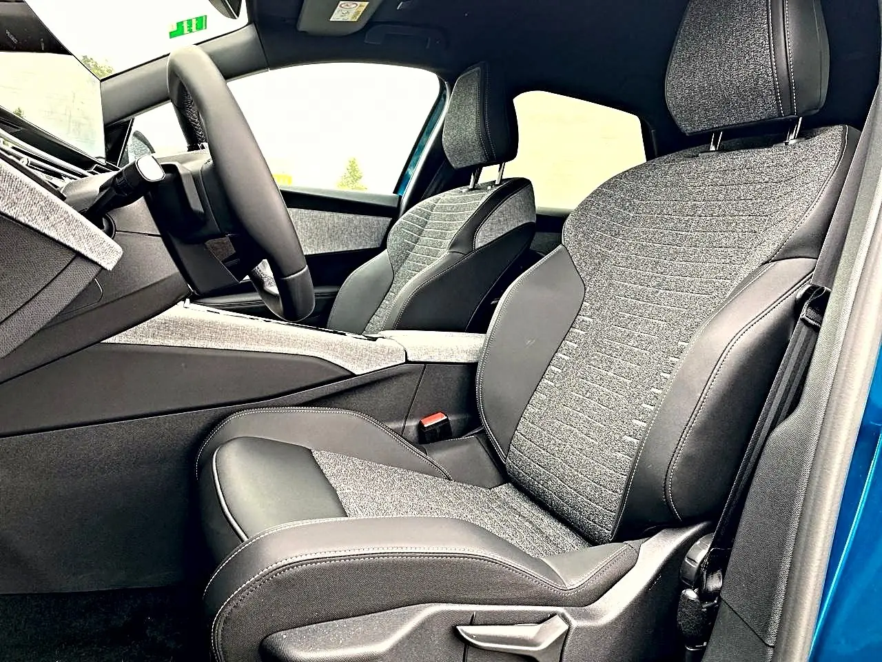 Vue intérieure côté conducteur du Peugeot 3008 bleu 2025, sièges tissu et cuir gris avec volant multifonction cuir.