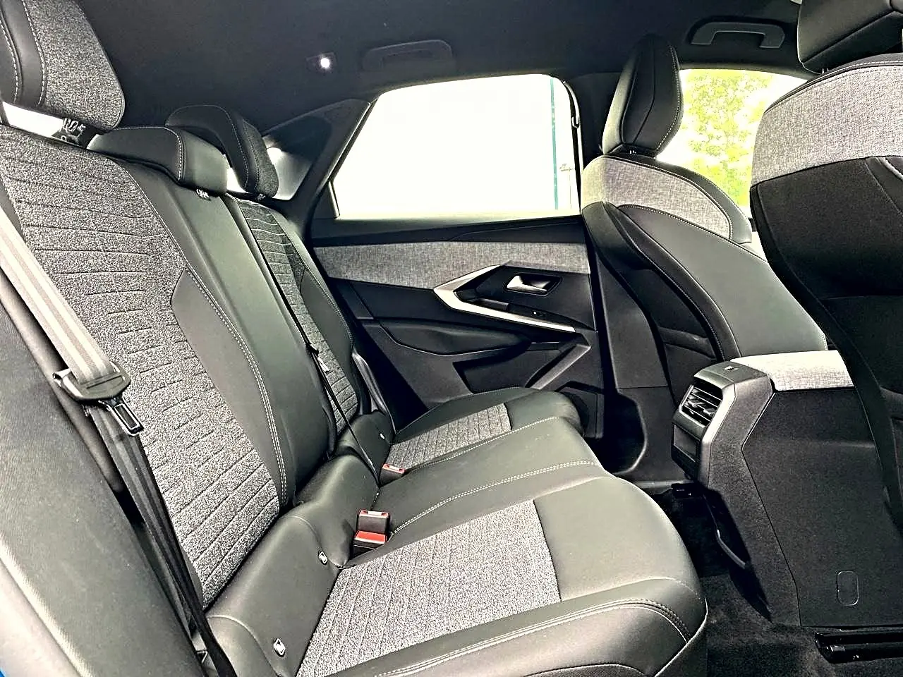 Vue intérieure arrière côté droit du Peugeot 3008 2025, sièges bi-matière gris et noir avec coutures contrastées.