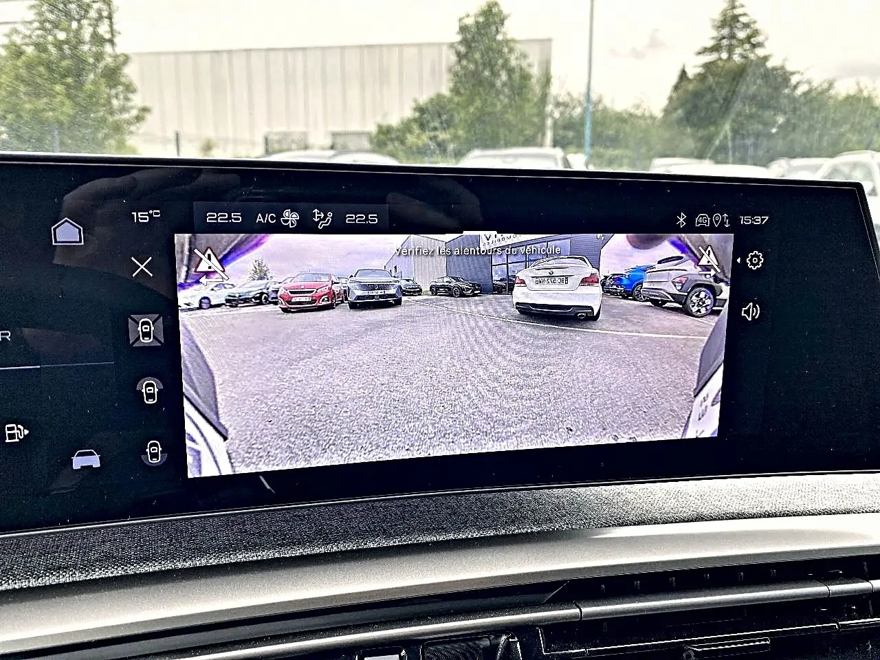 Écran tactile intérieur montrant la caméra de recul du Peugeot 3008 bleu, vue arrière du véhicule en stationnement.