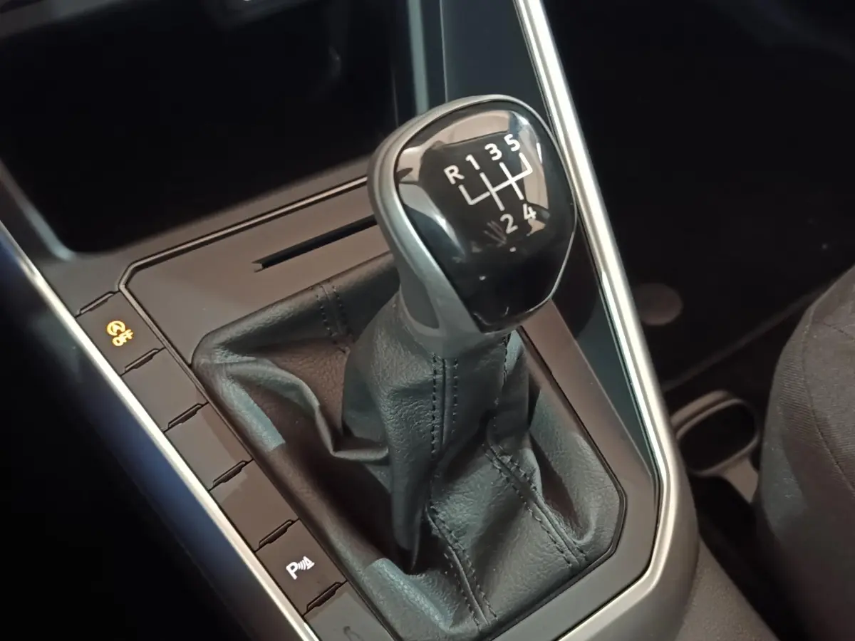 Gros plan sur le levier de vitesse manuel noir de la Volkswagen Polo 1.0 TSI 95 Life Plus, intérieur sombre.