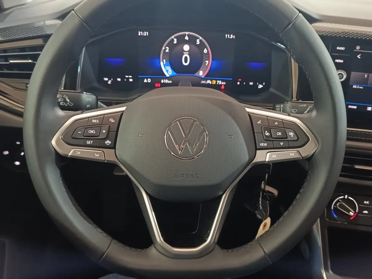 Vue rapprochée du volant multifonctions noir et cuir d'une Volkswagen Polo 2025 avec tableau de bord numérique.