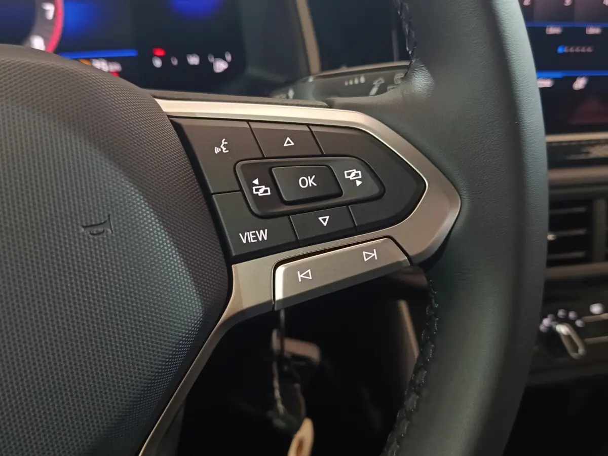 Gros plan sur les commandes multifonctions à droite du volant cuir du Volkswagen Polo gris foncé, avec affichage numérique en arrière-plan.
