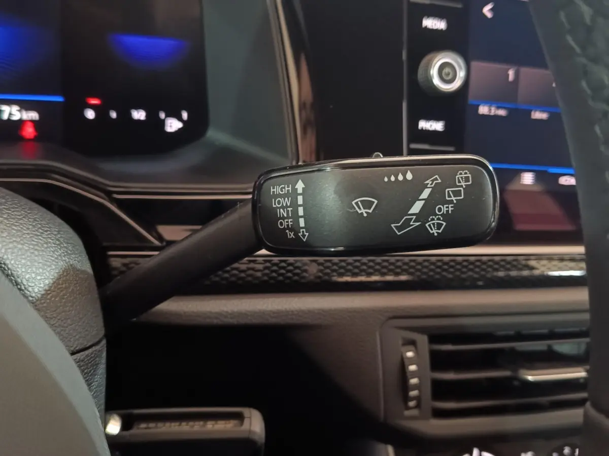 Gros plan sur la commande d’essuie-glace à gauche du volant dans l’habitacle d’une Volkswagen Polo gris foncé 2025.