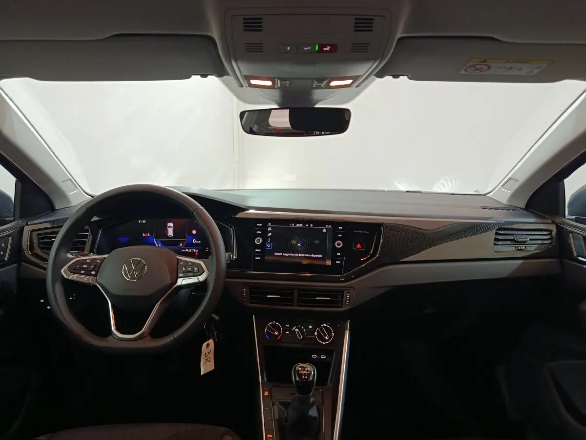 Vue intérieure avant du tableau de bord de la Volkswagen Polo gris foncé avec écran tactile et volant multifonctions.