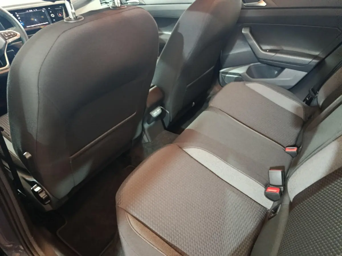 Vue intérieure arrière droite montrant la banquette et le dos des sièges avant de la Volkswagen Polo gris foncé.