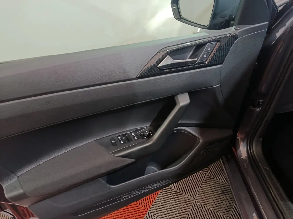 Vue intérieure côté gauche de la porte avant gris foncé de la Volkswagen Polo 2025 avec commandes électriques et poignée intégrée.