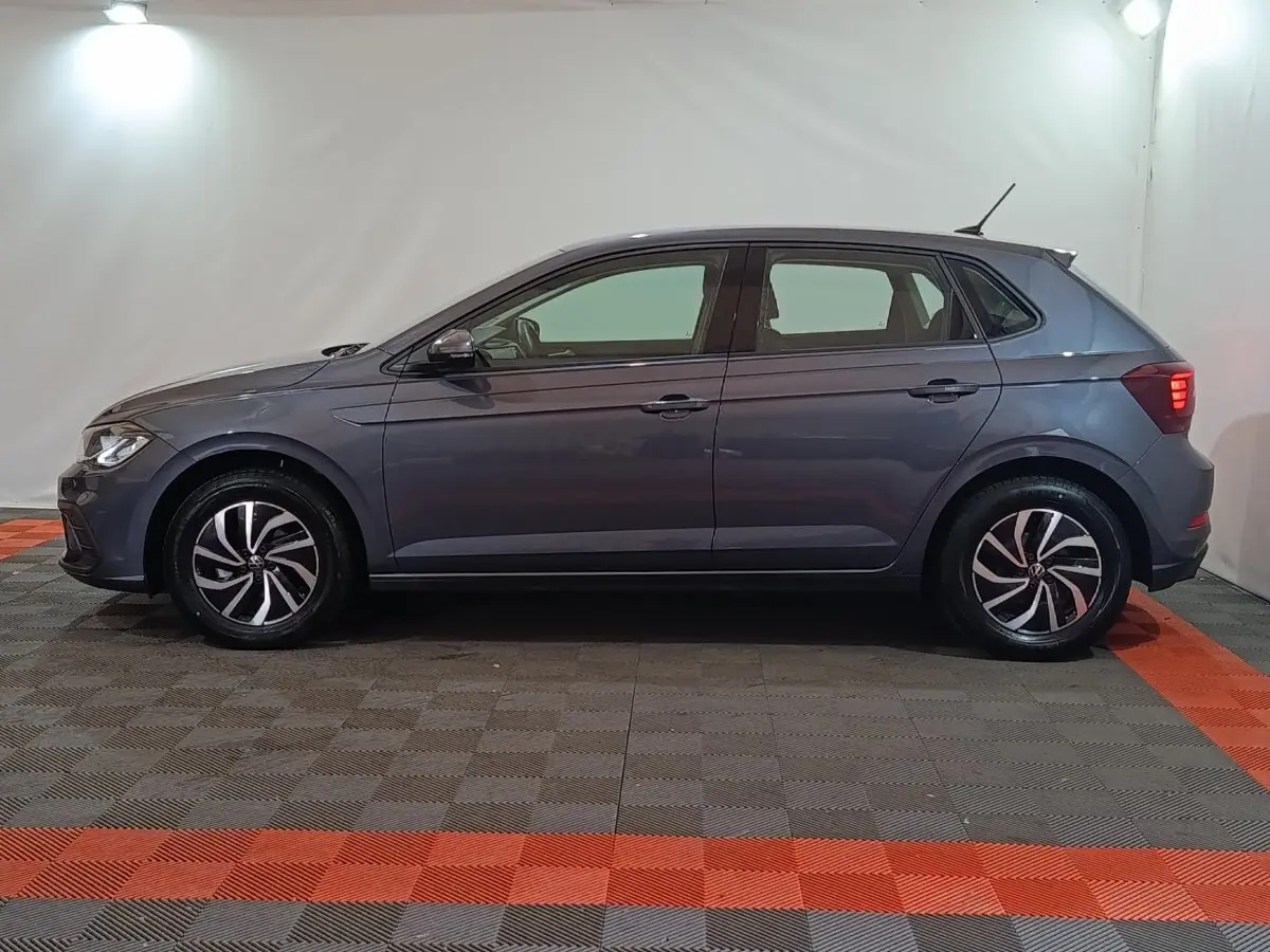 Vue latérale droite d'une Volkswagen Polo gris foncé 2025 avec jantes alliage et feux arrière allumés.