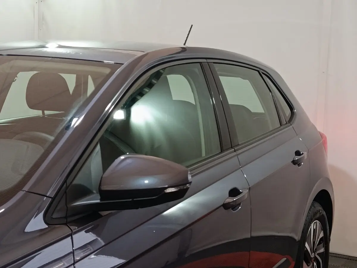 Vue côté gauche rapprochée d'une Volkswagen Polo gris foncé avec rétroviseur et poignées de porte visibles.