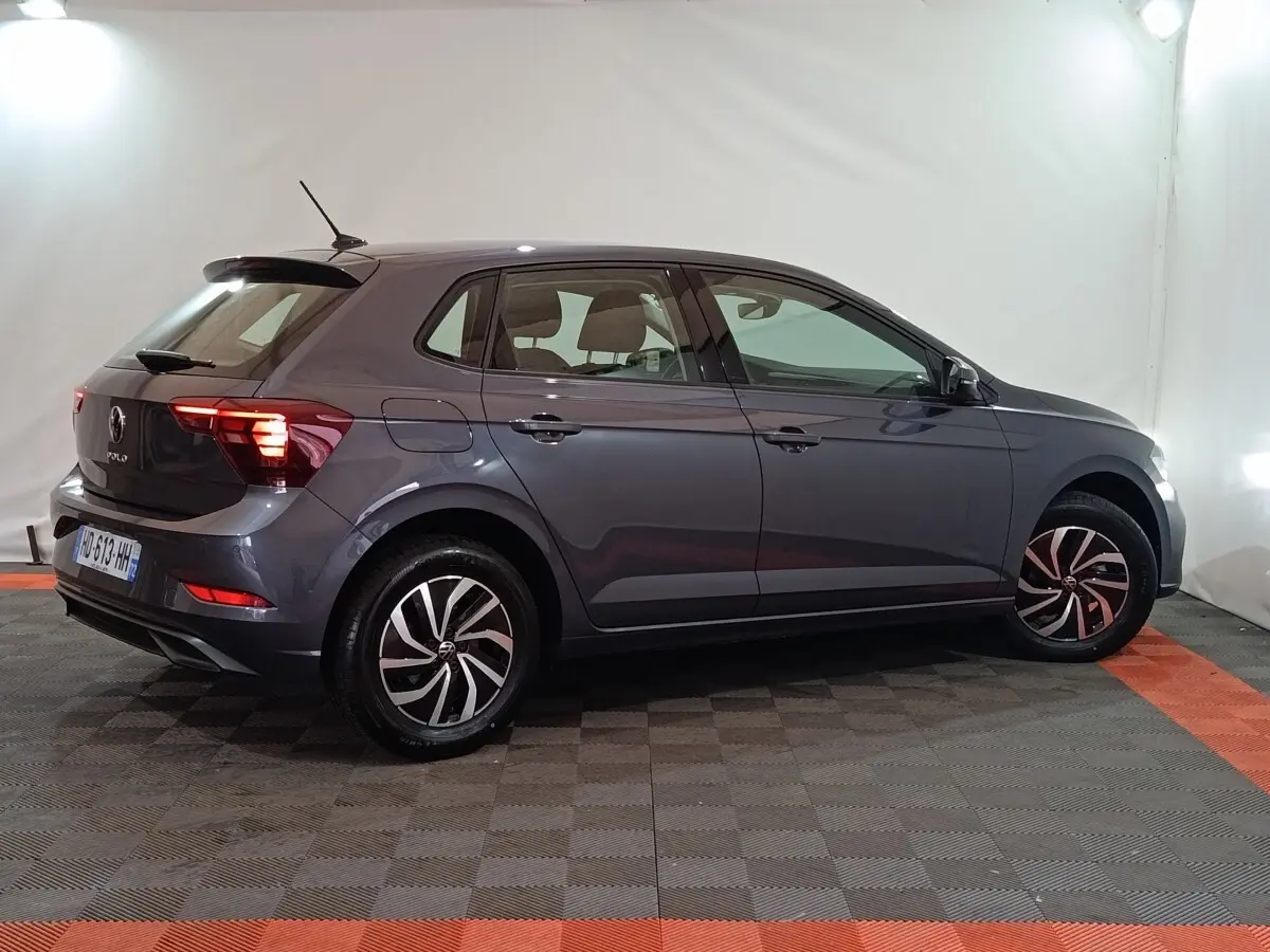 Volkswagen Polo gris foncé vue de profil côté droit, avec feux arrière LED allumés dans un studio.