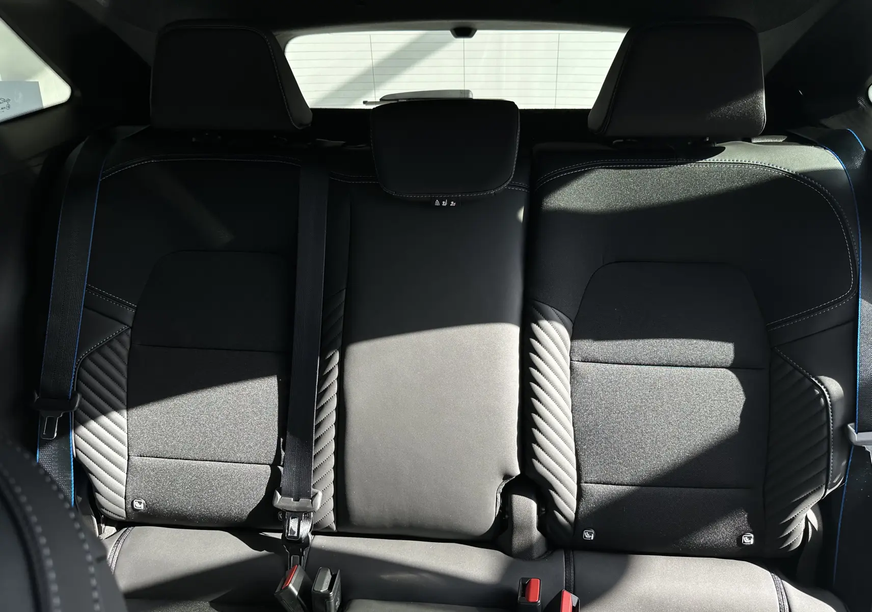 Vue arrière intérieure des sièges arrière noirs avec surpiqûres bleues du Renault Symbioz Esprit Alpine 2025.